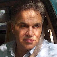 Eddie Dooley Unsmiling man with salt-and-pepper hair sitting in a vehicle driver's seat